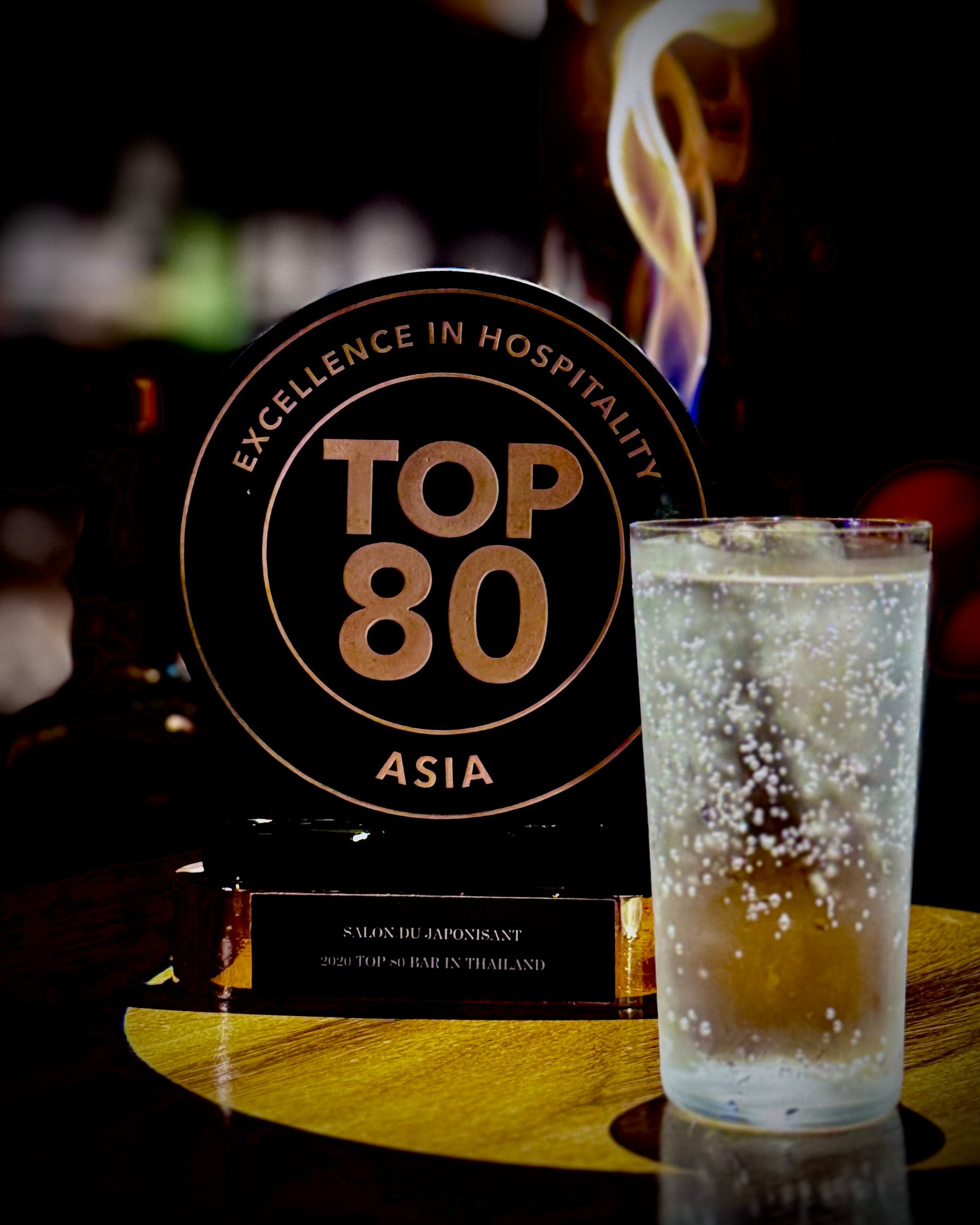 Salon du Japonisant's TOP 80 ASIA hospitality plaque beside a cocktail at the bar